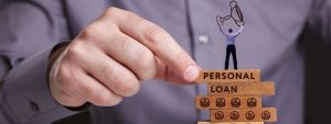 Close-up of man placing a 'Jenga' block with the blocks reading 'Personal Loan'